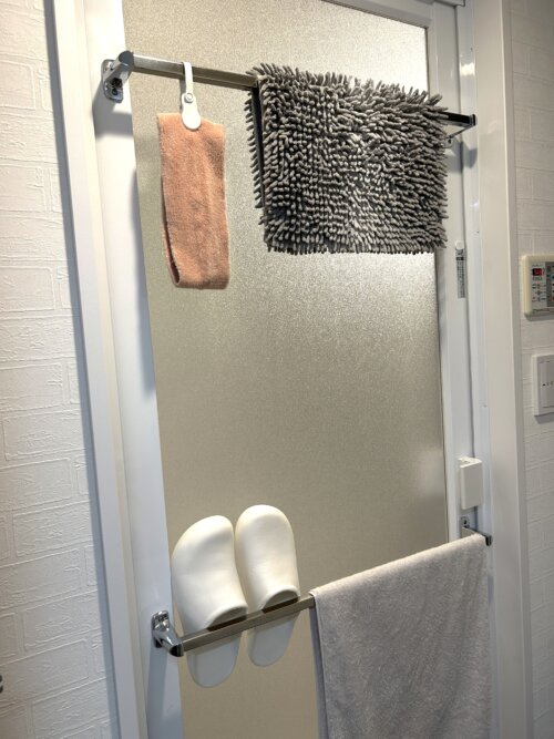 お風呂の開き戸の2本のタオルバーにタオル類やケユカのバススリッパをかけたところ